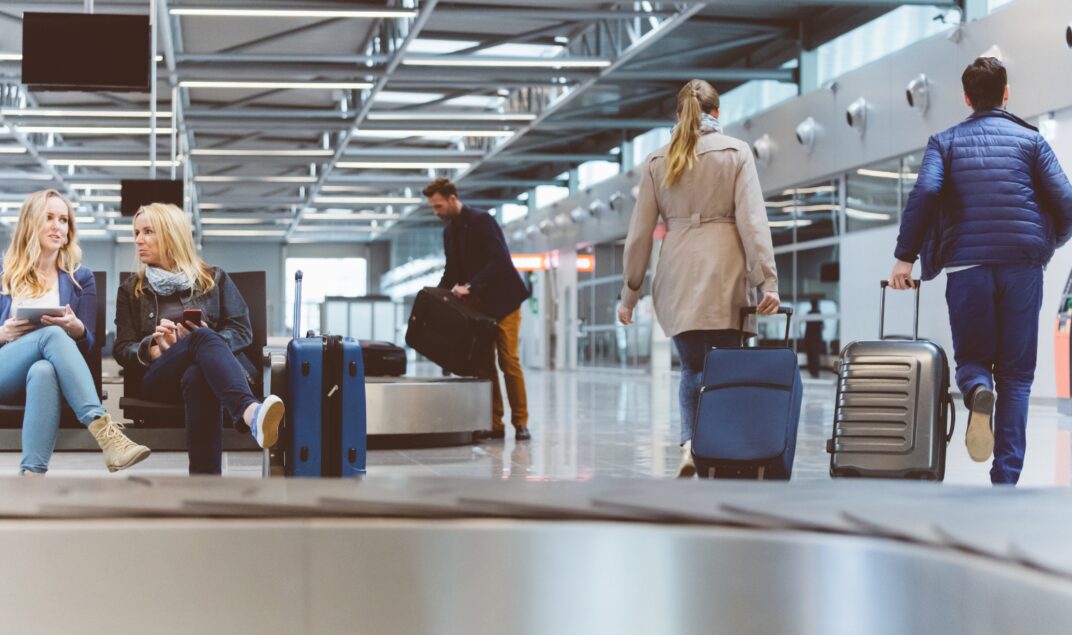 Pasajeros con valijas junto a la cinta de equipaje en un aeropuerto